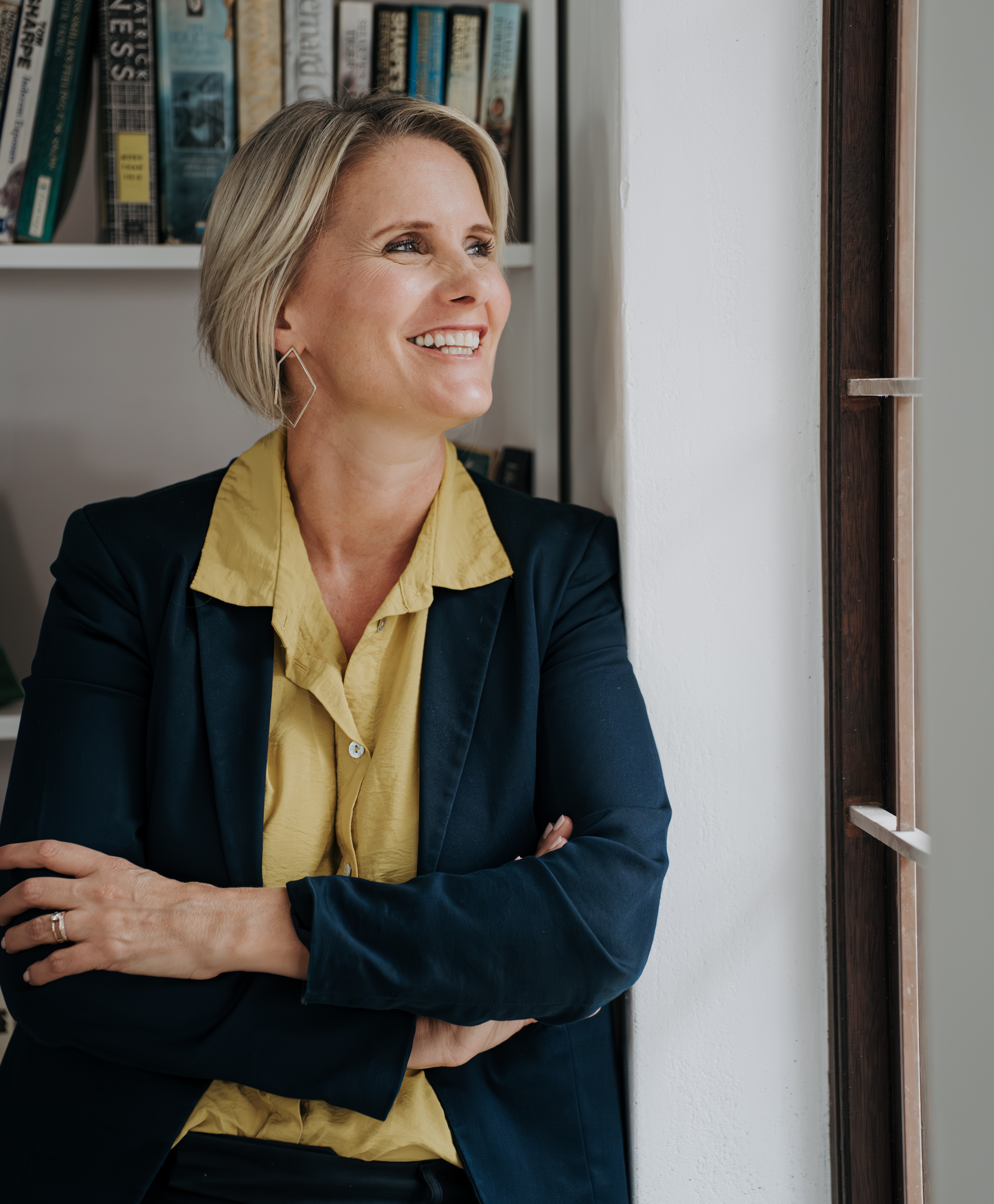 Professional portrait of a woman in a navy jacket and yellow blouse